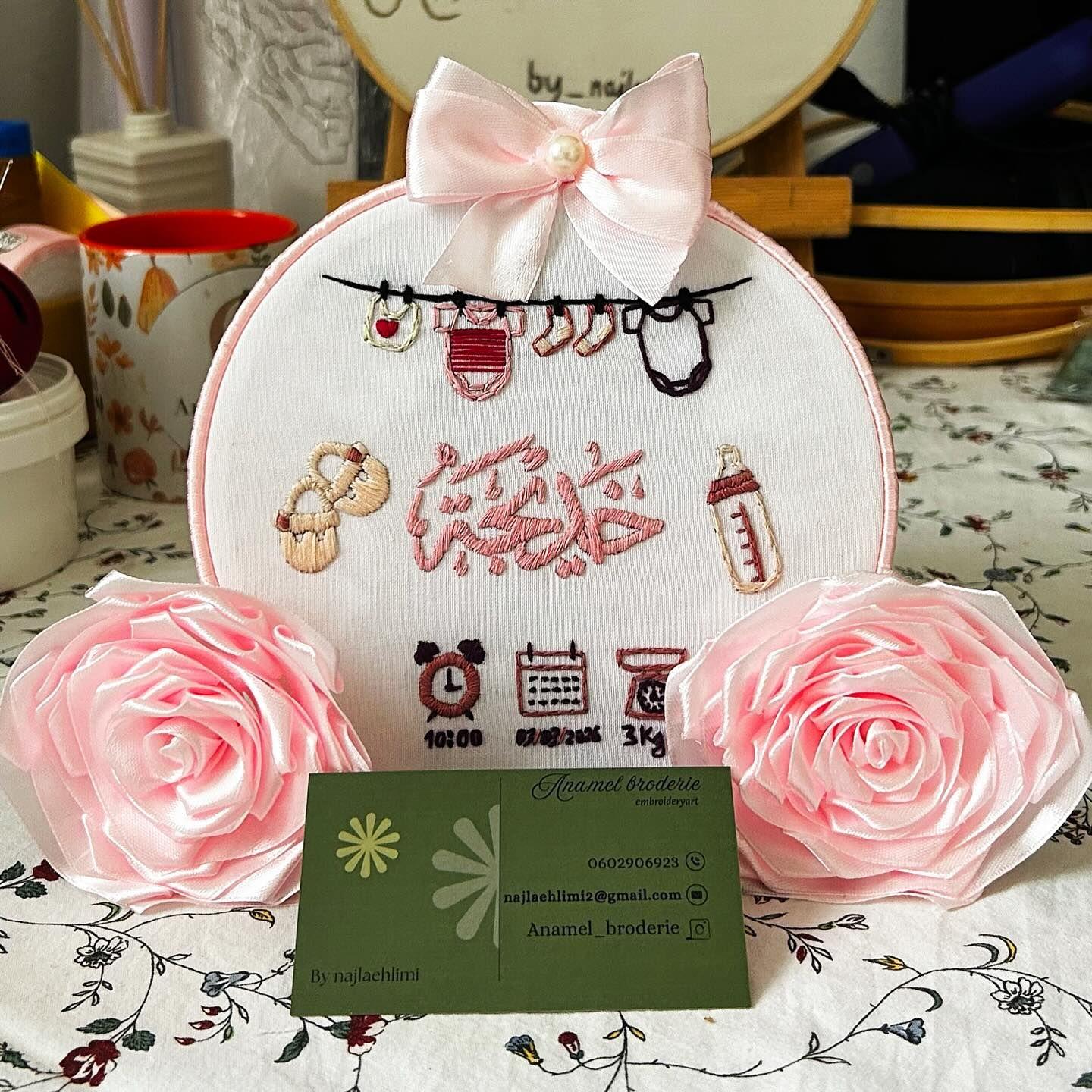 Tambour de naissance au prénom Khadija, gainé de ruban rose avec guirlande de vêtements de bébé