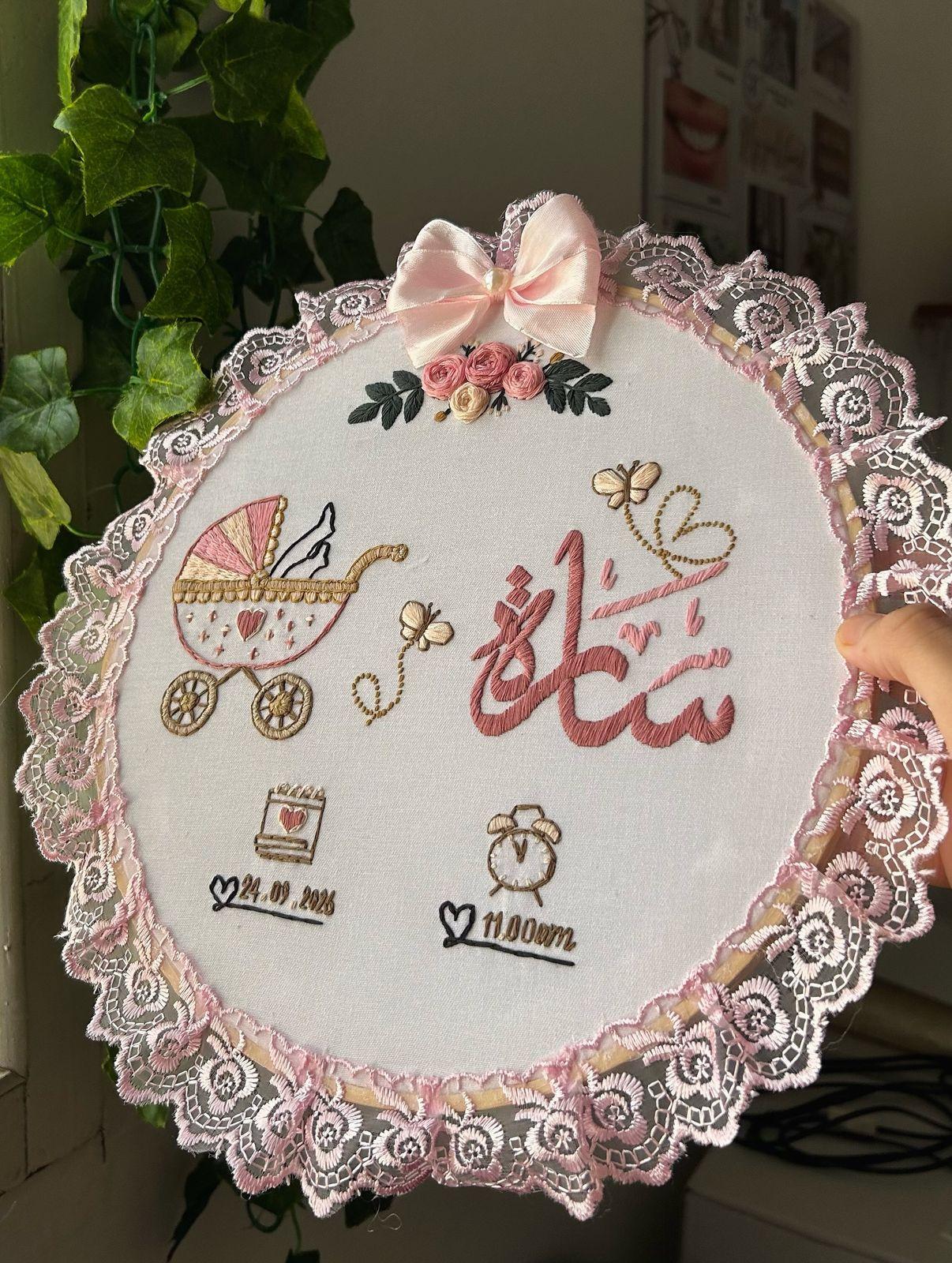 Tambour de naissance brodé au prénom Sara, bordé de dentelle rose avec un landau brodé